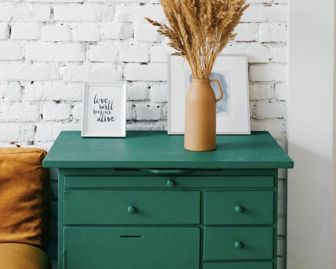 Green drawers picture in front of a wall composed of white bricks